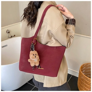 Detail of burgundy leather tote bag with plush bear charm and silk scarf decor