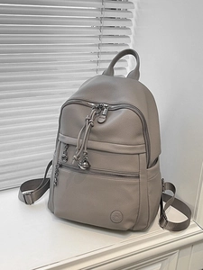 Grey pebbled leather backpack with multi-zipper design and metallic ring pendants