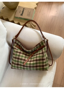 Detail der grün-braun karierten Tweed-Tasche mit Lederriemen und Metallbeschlägen