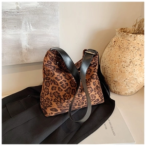 Close-up of leopard print tote bag featuring a black leather strap and golden metal buckle