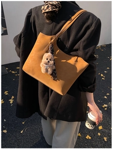 Detail of ginger leather tote bag with bear charm and adjustable shoulder strap