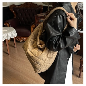 Detail of khaki quilted tote bag with stitched texture on a female shoulder