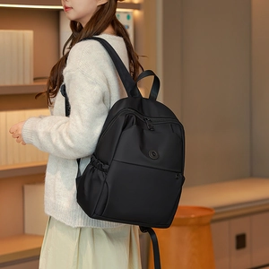 Detail of black waterproof nylon backpack with adjustable straps in a cozy indoor setting