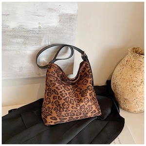 Detail of hobo leopard print bucket bag with black leather strap and textured fabric