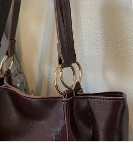 Détail du sac cabas en cuir ciré marron foncé avec anneau doré et coutures régulières