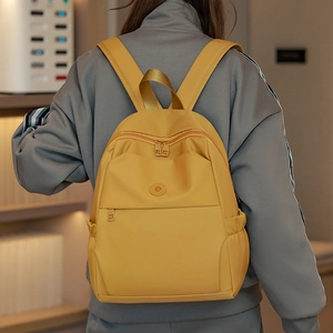 Back view of a vibrant yellow oxford backpack featuring a round logo and dual zipper pockets