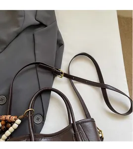 Détail de la bandoulière réglable et poignée à perles du sac seau marron foncé