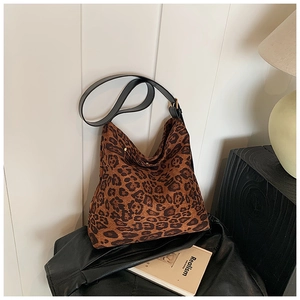 Detail of leopard print tote bag featuring a black shoulder strap and gold metal buckle