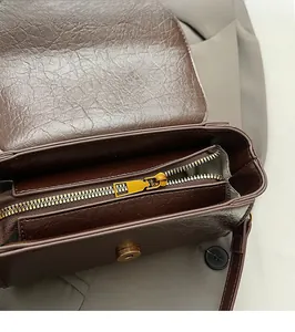Close-up of golden zipper detail and inner lining on brown oil-wax leather bag