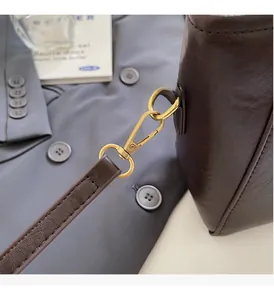 Détails d'un sac seau en cuir marron avec boucle en métal doré et coutures fines
