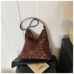 Close-up of leopard print tote bag featuring black leather strap and gold adjustment buckle