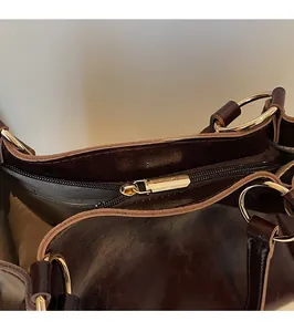 Détail de la fermeture éclair dorée et texture cuir vintage du sac fourre-tout