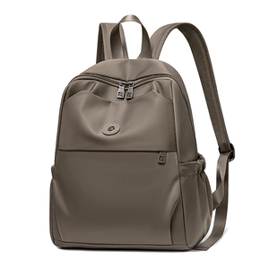 Detailed side view of brown nylon backpack with multiple compartments and smooth texture