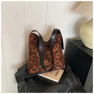 Detailed close-up of large leopard print hobo bag with black leather strap on books
