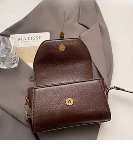 Detail of vintage brown leather Boston bag with magnetic closure on grey blazer