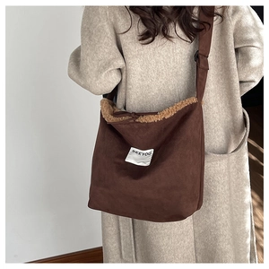 Detail of dark brown suede shoulder bag with plush faux shearling trim and white label