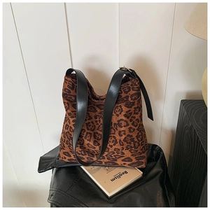 Detail of leopard print tote bag featuring black leather strap and metal buckle adjustment