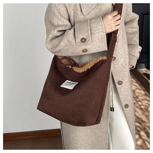 Detailed texture of brown suede crossbody bag with soft lamb wool trim and label