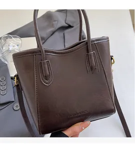 Détail du sac seau marron foncé avec logo embossé et boucle en métal doré élégante