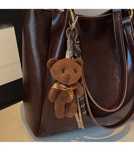 Détail d'un porte-clés ours en peluche marron avec ruban Love sur un sac en cuir