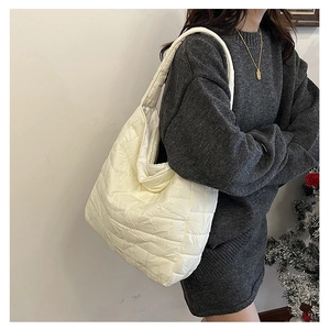 Detailed view of cream quilted puffer tote bag on shoulder with plush textured fabric
