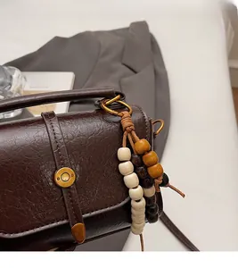 Detail of dark brown vintage faux leather texture with wooden bead pendant accessory