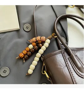 Détail d'un pendentif en perles de bois vintage avec fermoir doré sur un sac marron