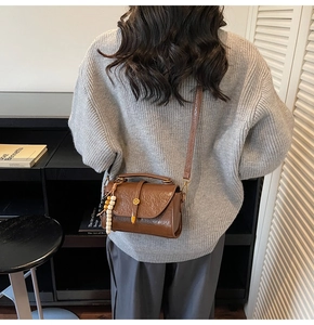Detailed view of brown vintage Boston bag with oil wax texture and bead charm