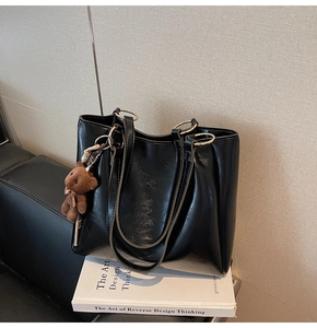 Détail du sac cabas noir brillant avec poignées en métal et breloque ours en peluche