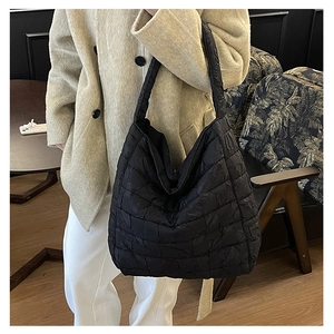 Detail of black quilted puffer tote bag with soft texture and square stitching patterns