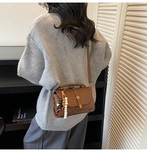 Brown vintage square crossbody bag with glossy leather finish and wood bead charm detail