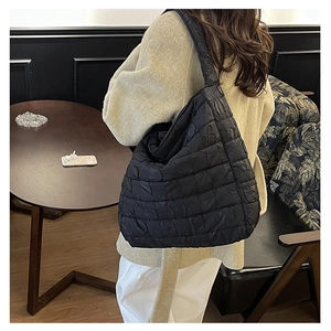 Detail of black quilted shoulder bag with lightweight puffer material and large capacity