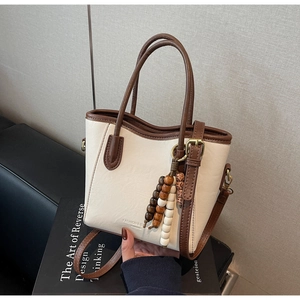 Détail du sac seau bicolore avec bordures contrastées et pendentif en perles de bois
