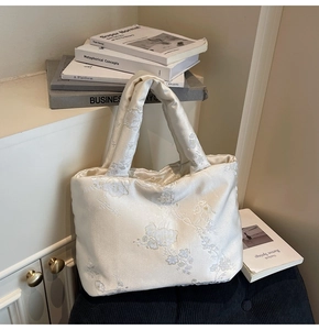 Detail of elegant cream satin quilted handbag with delicate floral embroidery and vintage style