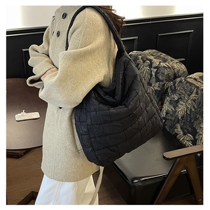Detailed view of the large black quilted shoulder bag in a stylish cafe setting