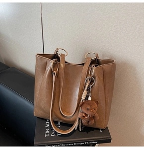 Détail du sac cabas marron café avec poignée en anneau métal et breloque ours
