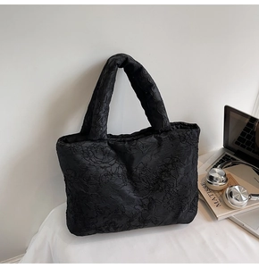 Detailed close-up of black floral textured fabric on a large quilted tote bag