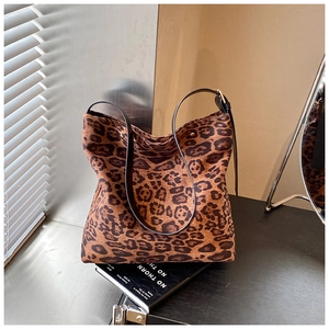 Detail view of the leopard print bucket bag featuring a black strap and golden buckle