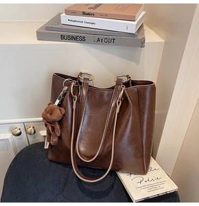 Gros plan d'un grand sac cabas marron foncé avec un ours en peluche et des anneaux en métal