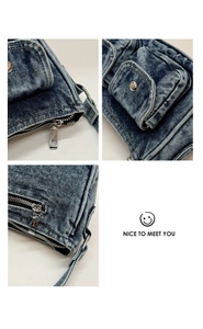 Close-up of blue washed denim texture with silver metal zippers and multi-pocket details