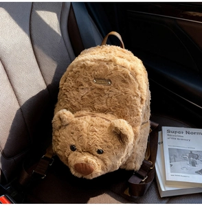 Detail of Lovely Bear plush backpack showing teddy bear texture and gold metal plaque