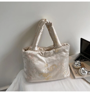 Detailed view of champagne satin tote bag with traditional Chinese embroidery and padded texture