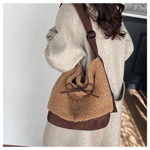 Detail of plush brown shoulder bag with bow and TEME embroidery on a model