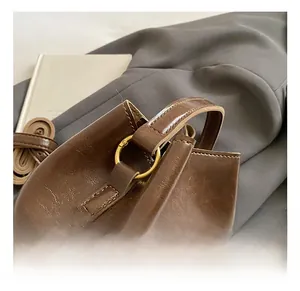 Gros plan de la boucle dorée et de la texture du cuir marron sur le sac seau