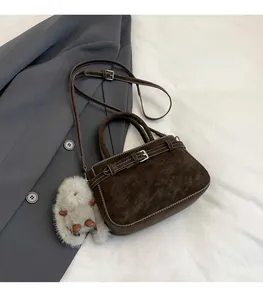 Dettaglio borsa a mano marrone scuro scamosciata con fibbia decorativa e ciondolo morbido