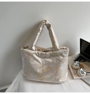Detail of champagne gold satin tote bag with traditional Chinese embroidery on a desk