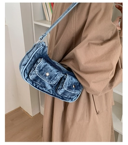 Detail shot of vintage blue washed denim baguette bag with flap pockets and buckles