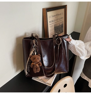 Détails d'un cabas marron foncé avec anneaux dorés et pendentif ours en peluche mignon