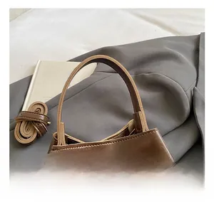 Vue détaillée du sac seau en cuir ciré marron foncé avec poignée et bandoulière