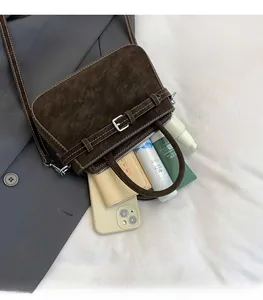 Dettaglio della borsa in pelle scamosciata marrone con spazio per cellulare e trucchi